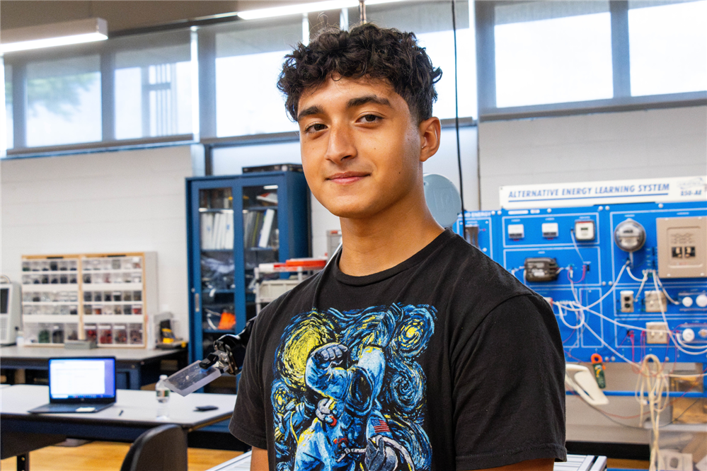 Matteo stands in a classroom. Awards recognize high-performing students.